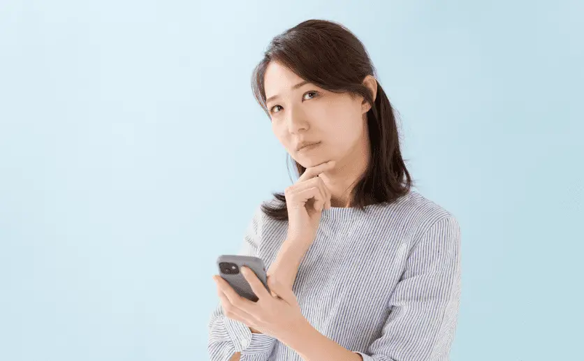 スマホを操作しながら悩む女性