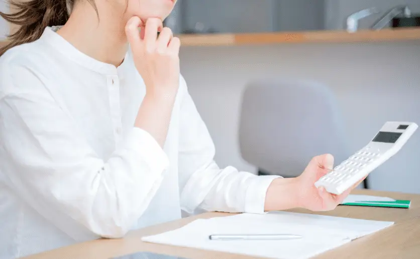 電卓を眺めながら悩む女性